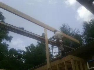 Carpenter setting a ridge beam over a new addition frame — Ice Dam Removal by Roofing Brothers in Freedom