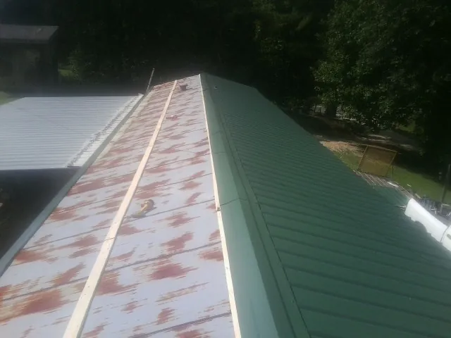 Old rusted panels beside newly installed green metal roofing — Wind Damage Roof Repair by Roofing Brothers in Freedom