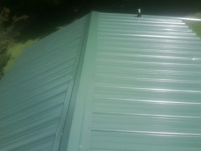 New green metal panels meeting at the ridge of a roof — Flat Roof Repair work by our crew in Freedom
