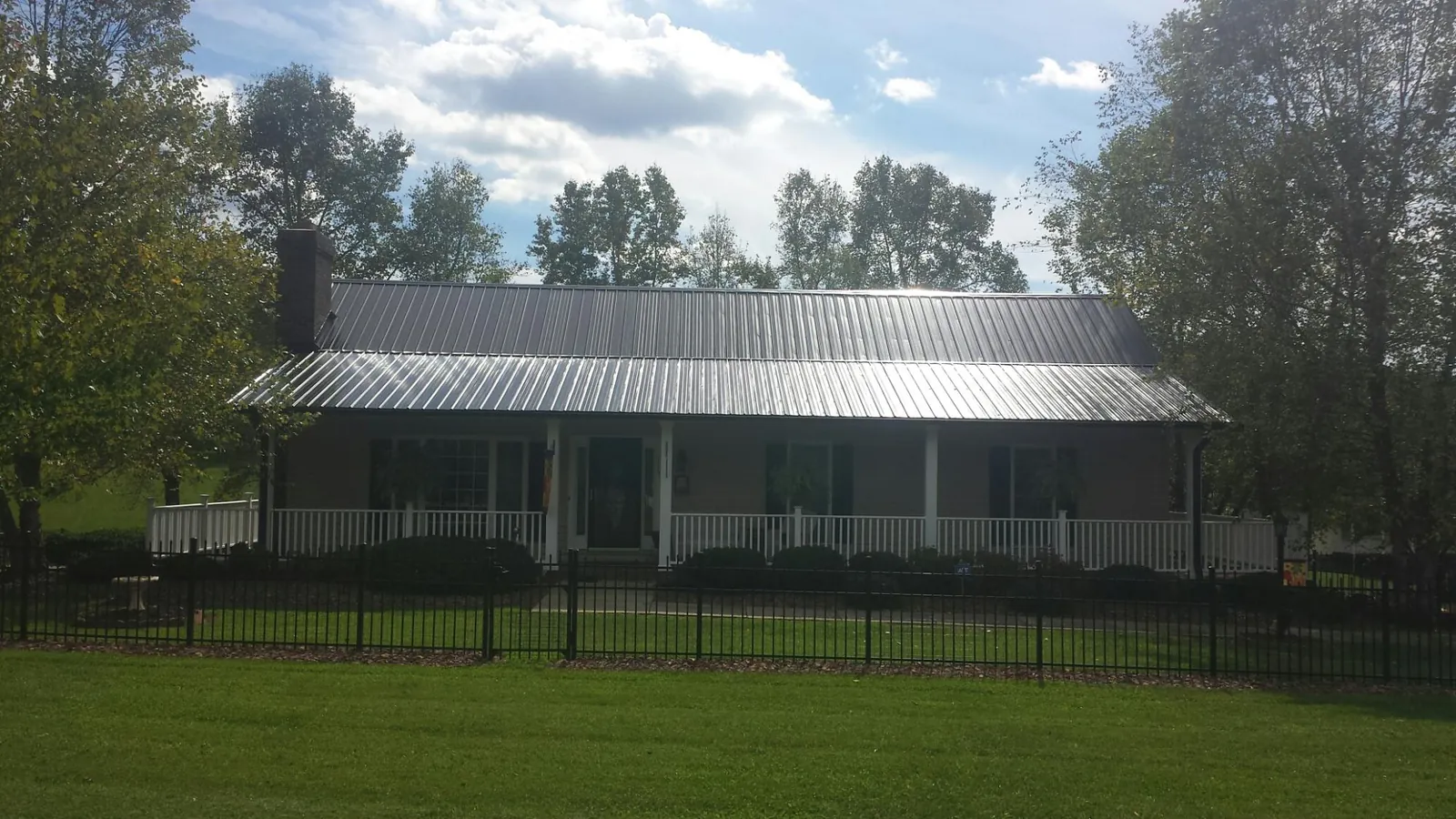 Gray metal roof on a brick ranch with a full width front porch — Gutter Guard Installation work by our crew in Freedom