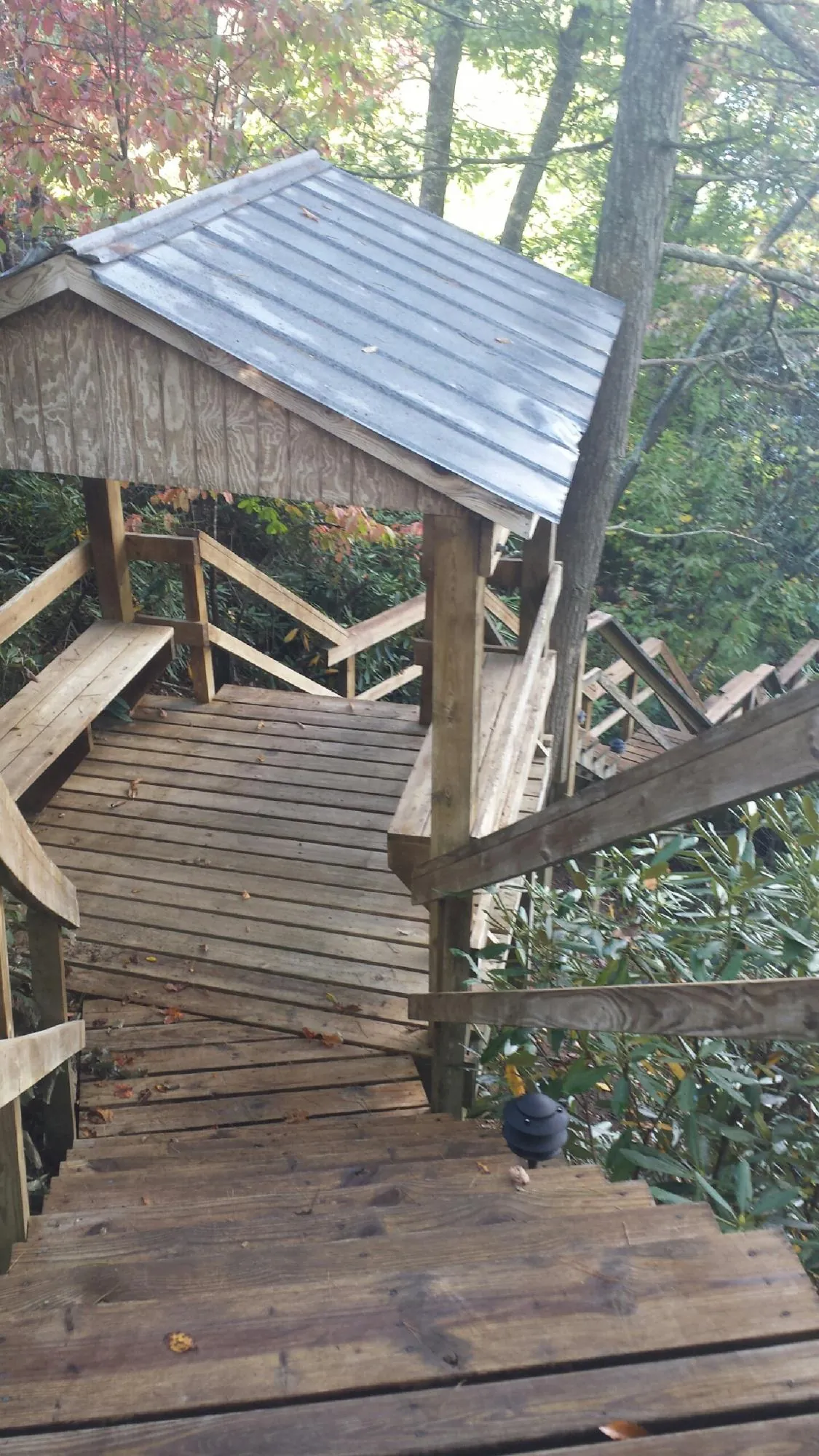 Metal roofed shelter over wooden steps on a wooded walkway — Skylight Repair & Installation work by our crew in Freedom